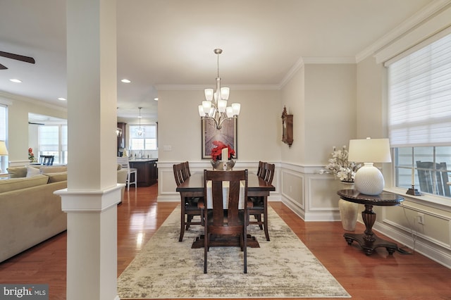 dining area featuring ceiling fan with notable chandelier, hardwood / wood-style flooring, ornate columns, and ornamental molding