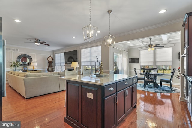 kitchen featuring pendant lighting, a center island, coffered ceiling, light hardwood / wood-style flooring, and ornamental molding