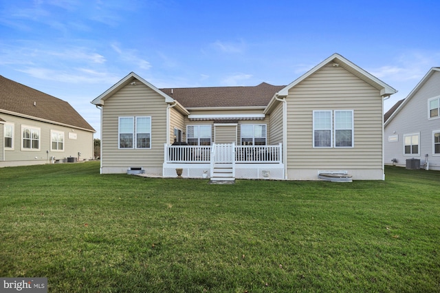 rear view of property featuring cooling unit, a wooden deck, and a lawn