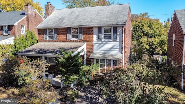 view of front of property with brick siding, a chimney, and roof with shingles