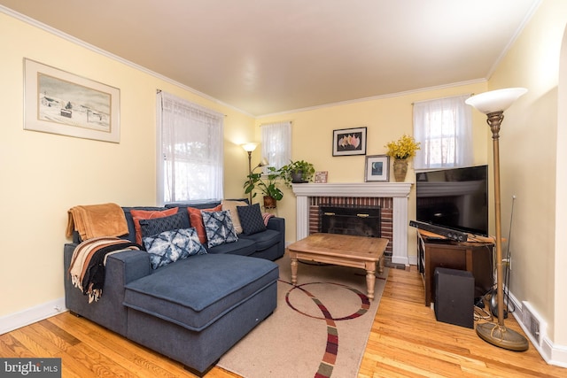 living room featuring visible vents, a brick fireplace, crown molding, baseboards, and wood finished floors