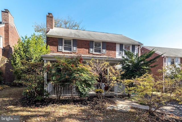 view of front facade with brick siding, roof with shingles, and a chimney