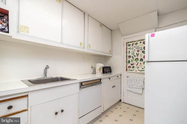 kitchen with a sink, white cabinetry, white appliances, light countertops, and light floors