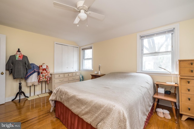 bedroom with a closet, light wood-style flooring, lofted ceiling, and ceiling fan