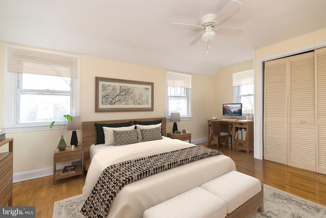 bedroom with a closet, a ceiling fan, baseboards, and wood finished floors