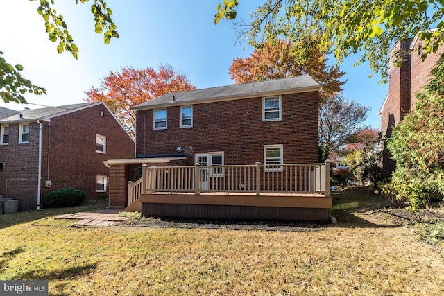 rear view of house with a lawn, brick siding, and a wooden deck