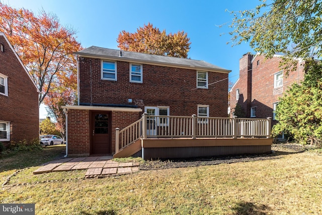 rear view of house with a deck, a lawn, and brick siding