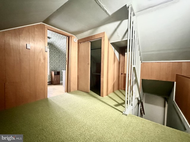 bonus room featuring wood walls, light carpet, and vaulted ceiling