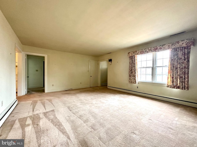 carpeted empty room featuring a baseboard heating unit