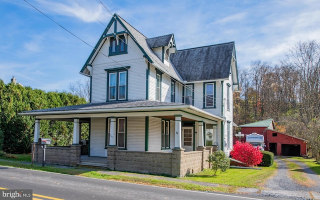 view of front of house with a porch, a garage, and an outbuilding