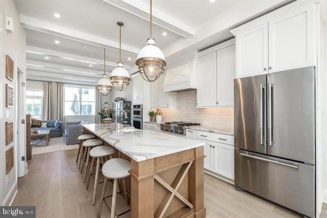 kitchen featuring beamed ceiling, white cabinetry, a kitchen island with sink, and appliances with stainless steel finishes