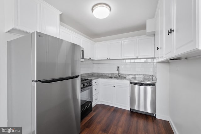 kitchen with white cabinets, sink, light stone countertops, appliances with stainless steel finishes, and dark hardwood / wood-style flooring