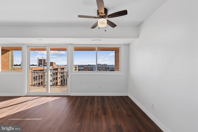 unfurnished room with ceiling fan, dark wood-type flooring, and a wealth of natural light