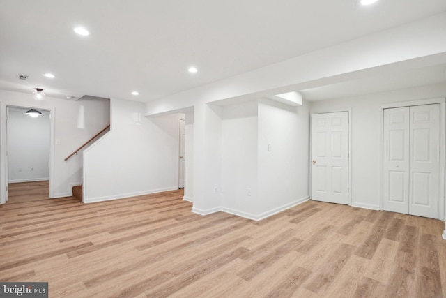 finished below grade area featuring baseboards, stairway, light wood-style flooring, and recessed lighting