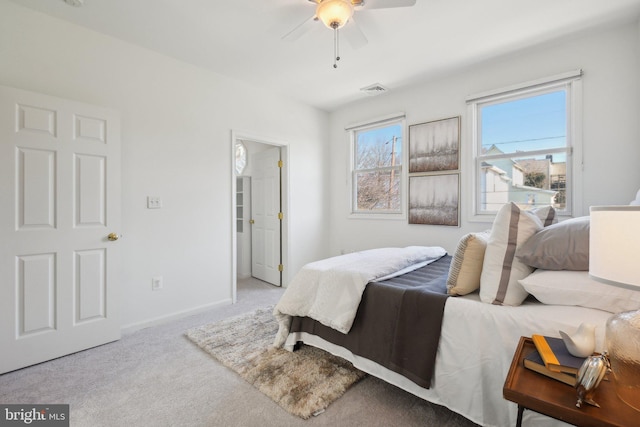 carpeted bedroom featuring a ceiling fan, visible vents, and baseboards