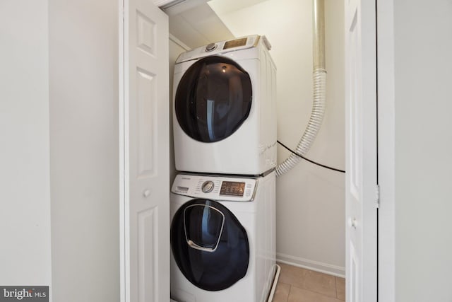 clothes washing area featuring stacked washer and dryer, light tile patterned flooring, and laundry area