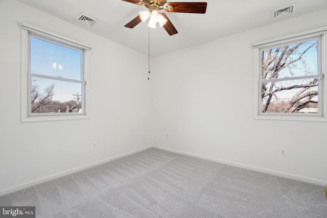 carpeted spare room with plenty of natural light, visible vents, and baseboards