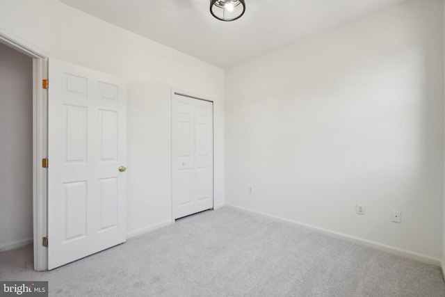 unfurnished bedroom featuring carpet, baseboards, and a closet