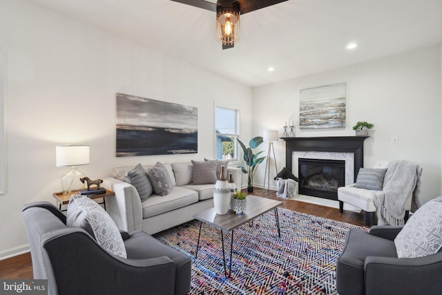 living room featuring a fireplace, baseboards, wood finished floors, and recessed lighting