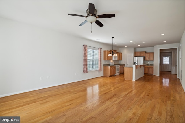 unfurnished living room featuring light hardwood / wood-style flooring, ceiling fan, and a healthy amount of sunlight