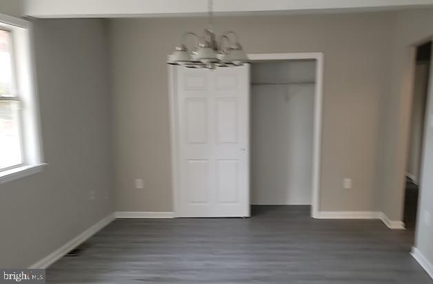 unfurnished bedroom featuring a chandelier and dark wood-type flooring