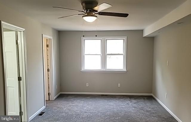 unfurnished bedroom featuring dark colored carpet and ceiling fan