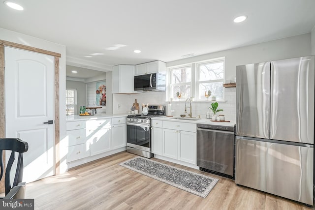 kitchen featuring white cabinetry, sink, light hardwood / wood-style floors, and appliances with stainless steel finishes