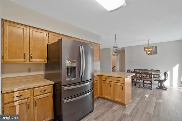 kitchen with an inviting chandelier, stainless steel refrigerator with ice dispenser, light wood-type flooring, decorative light fixtures, and kitchen peninsula