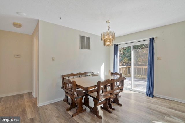 dining space with a notable chandelier and light hardwood / wood-style floors