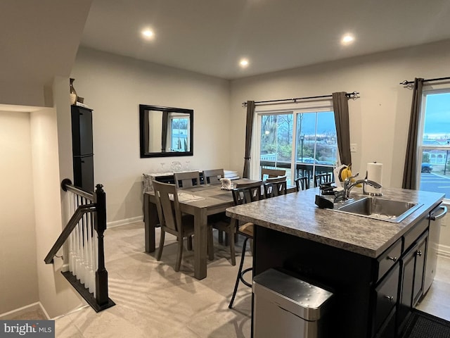 kitchen featuring sink, a kitchen island with sink, and light carpet