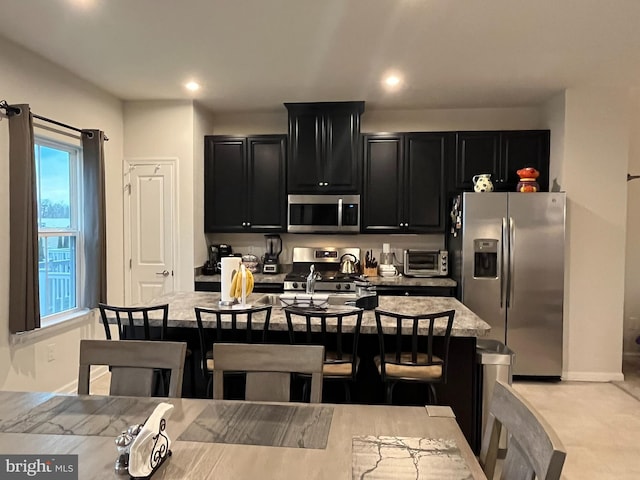 kitchen featuring a kitchen bar, sink, stainless steel appliances, and an island with sink