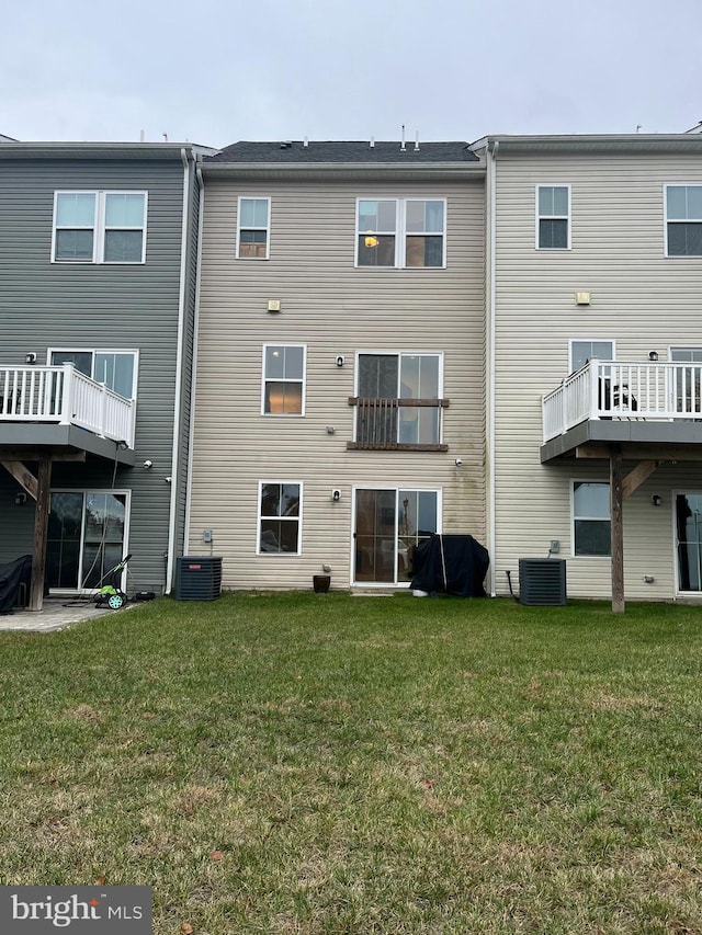 back of house with central AC unit and a yard