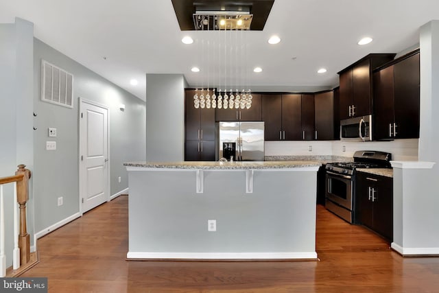 kitchen with a kitchen island, light hardwood / wood-style floors, stainless steel appliances, and a breakfast bar area