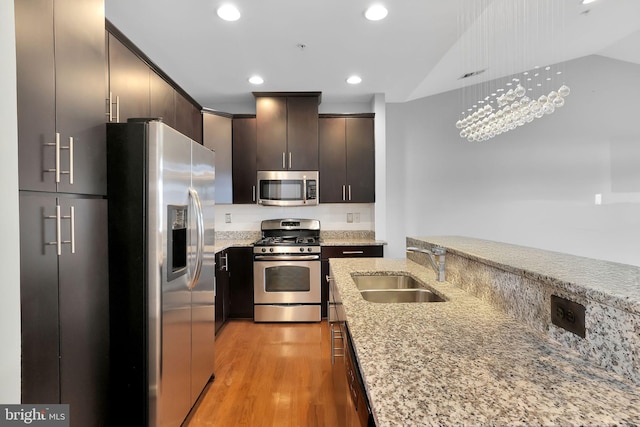 kitchen featuring sink, vaulted ceiling, light wood-type flooring, dark brown cabinetry, and stainless steel appliances