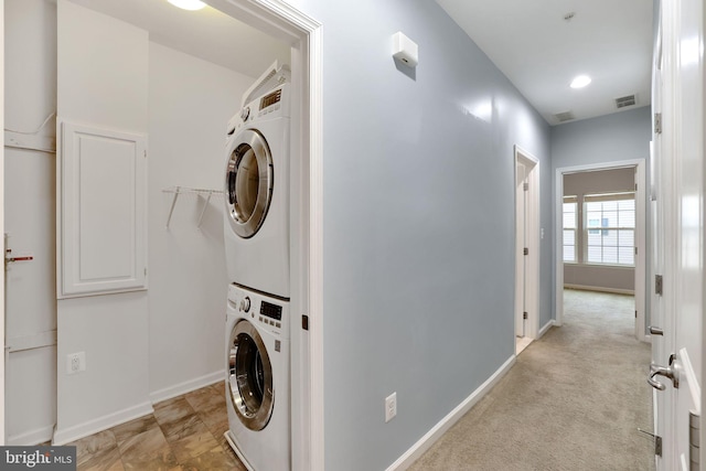 laundry room with light carpet and stacked washer and dryer