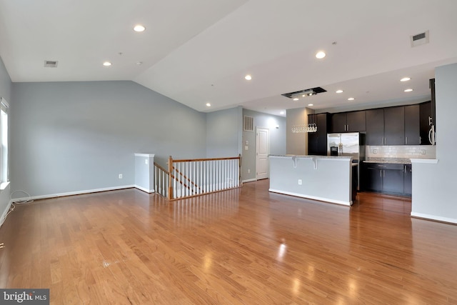 unfurnished living room with light wood-type flooring and vaulted ceiling