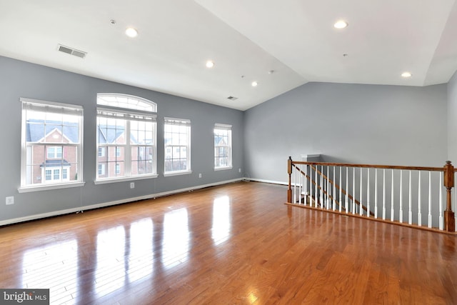 empty room featuring light wood-type flooring, a wealth of natural light, and lofted ceiling