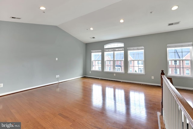 spare room featuring lofted ceiling and light wood-type flooring