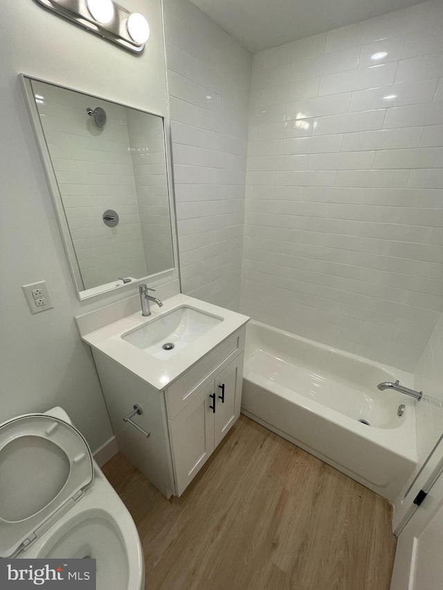 full bathroom with vanity, wood-type flooring, tiled shower / bath combo, and toilet