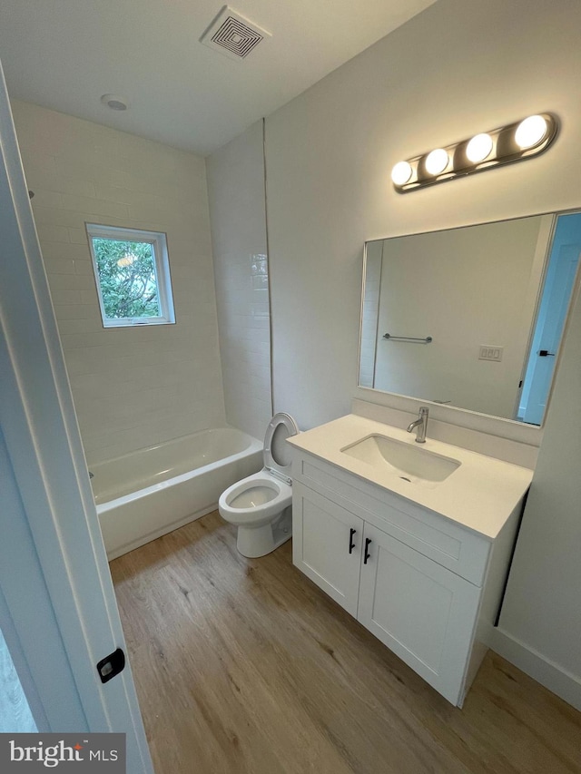 full bathroom with hardwood / wood-style flooring, vanity, toilet, and tiled shower / bath