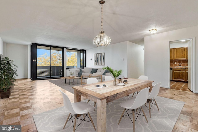 dining space featuring floor to ceiling windows, an inviting chandelier, light parquet floors, sink, and a textured ceiling