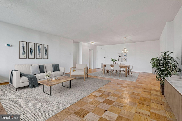 living room with a textured ceiling, a notable chandelier, and light parquet flooring