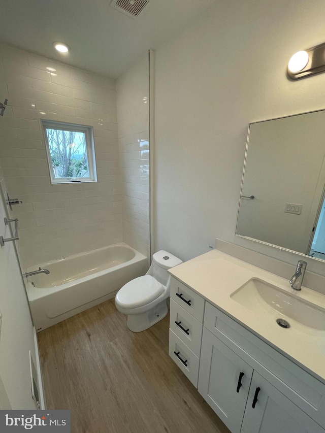 full bathroom featuring vanity, hardwood / wood-style flooring, toilet, and tiled shower / bath