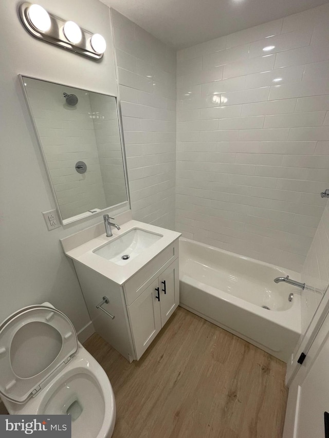 full bathroom featuring toilet, vanity, tiled shower / bath combo, and hardwood / wood-style flooring