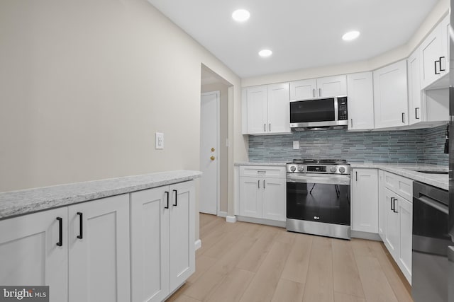 kitchen with white cabinets, light wood-type flooring, and appliances with stainless steel finishes