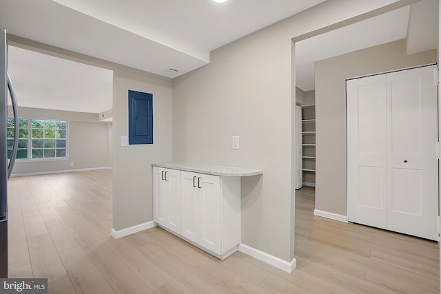 kitchen with white cabinets, electric panel, and light hardwood / wood-style floors