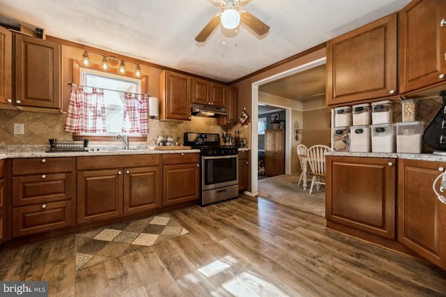 kitchen with crown molding, wood-type flooring, backsplash, and stainless steel stove