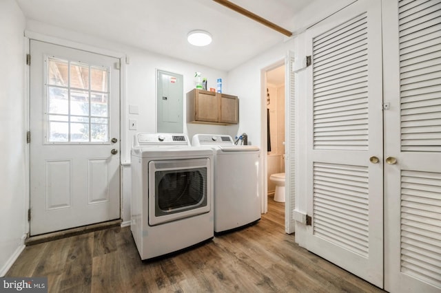 washroom with cabinets, wood-type flooring, electric panel, and washing machine and clothes dryer