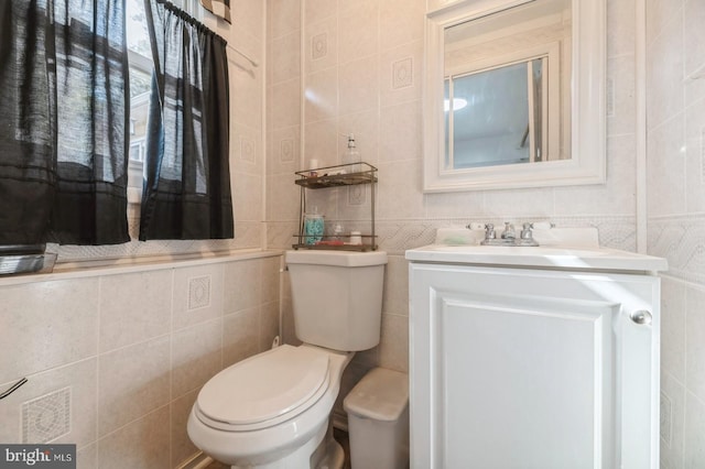 bathroom with vanity, tile walls, and toilet