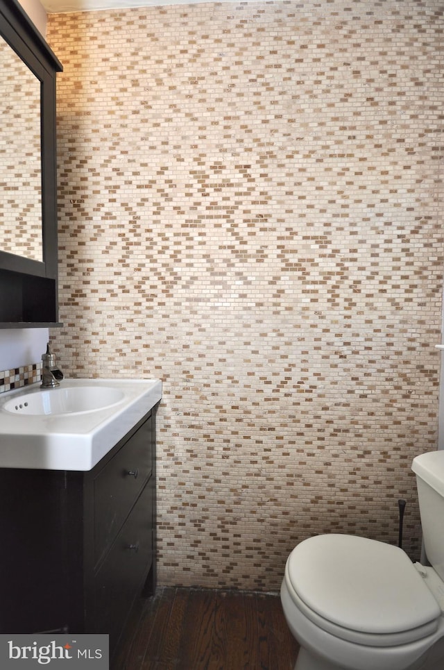 bathroom with hardwood / wood-style floors, vanity, tile walls, and toilet